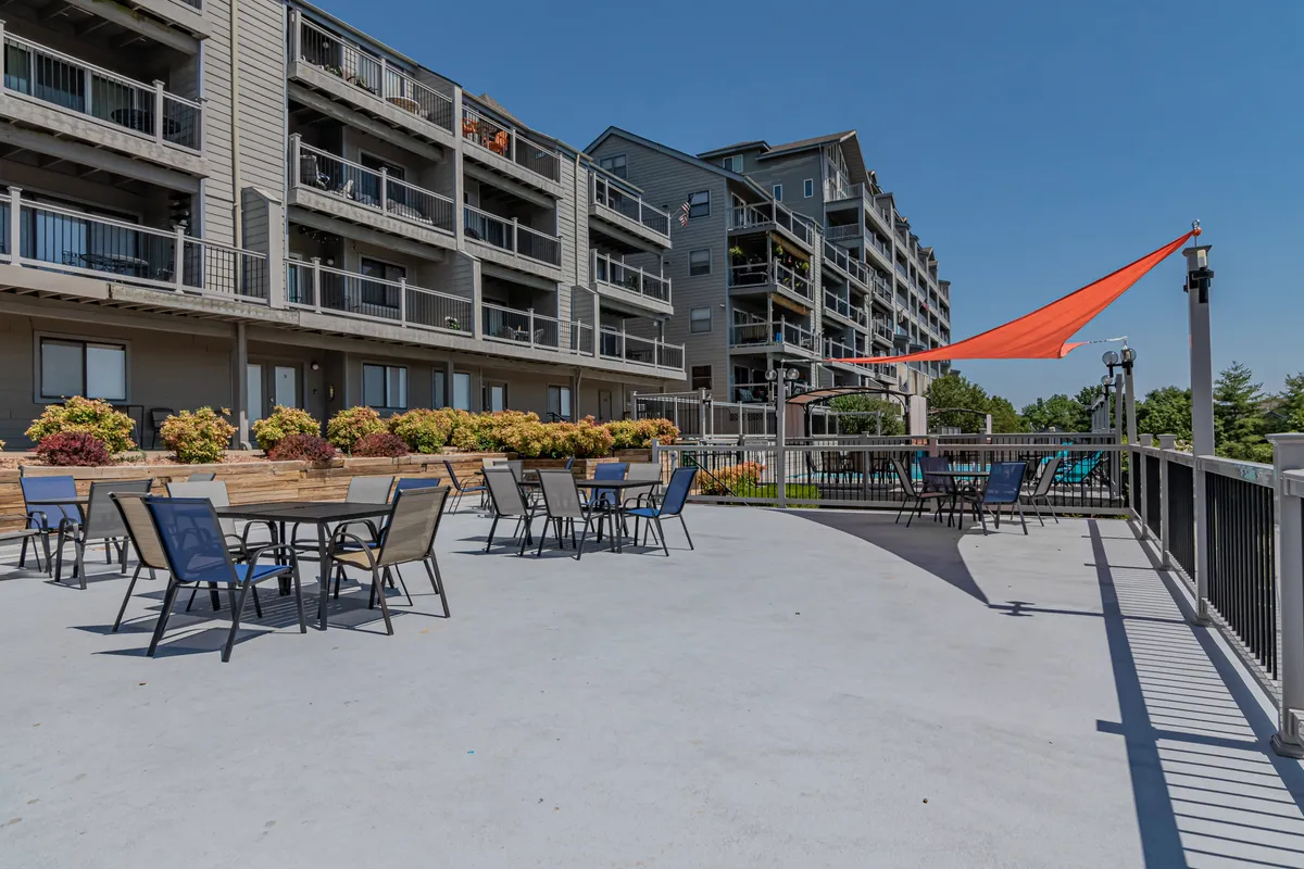 A lively outdoor seating area adorned with colorful planters and an orange shade sail, offering a cheerful spot for gatherings, relaxing, or outdoor dining. The space feels open and family-friendly.