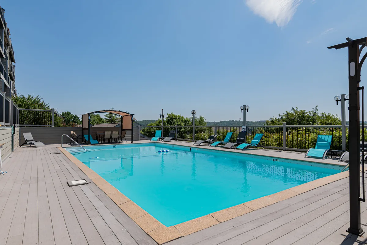 The outdoor swimming pool sits surrounded by comfortable lounge chairs and a shaded cabana. The inviting water and sunlit setting offer a lively yet relaxing spot for cooling off or spending time with family and friends after a day on the lake.