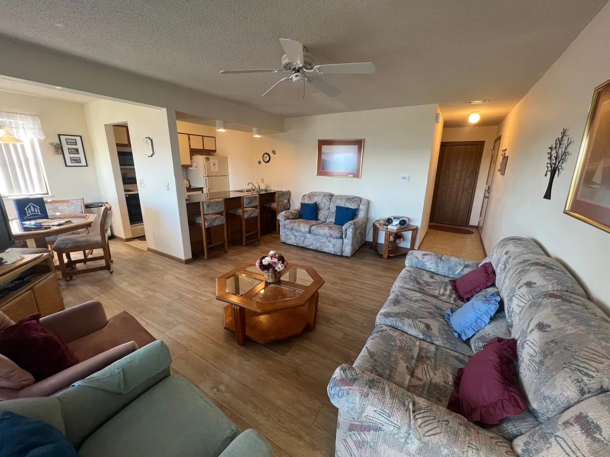 The image showcases a spacious and inviting open-concept living area with comfortable sofas, a stylish coffee table, a welcoming dining space, and a modern kitchen counter. The scene is bright and airy, perfect for gathering with family or friends for meals, games, or relaxation after a day of Branson adventures.