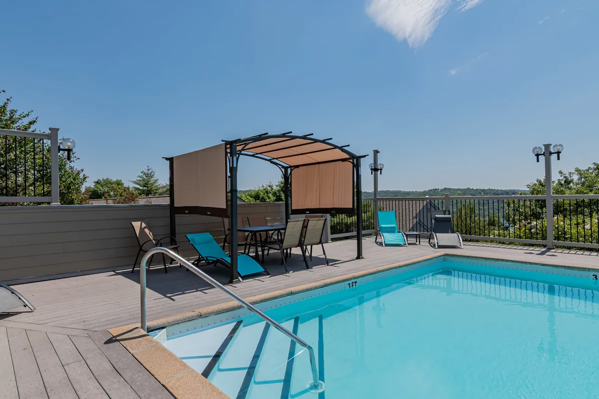 This exterior shot captures the inviting resort swimming pool surrounded by lounge chairs and a gazebo, all set against a well-maintained landscape. The pool is the focal point, suggesting plenty of space for swimming, sunbathing, and socializing in a vibrant outdoor setting.